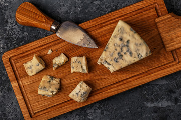 Pieces of blue cheese on wooden serving board.