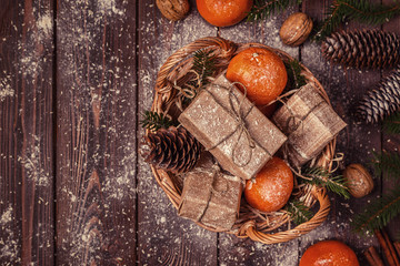 Christmas composition with tangerines, gift boxes, cones on a dark wooden background.