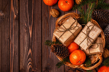 Christmas composition with tangerines, gift boxes, cones on a dark wooden background.