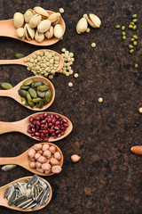 Assortment of beans and lentils in wooden spoon on teak wood background