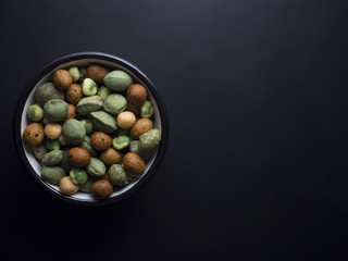 Japanese wasabi crackers in small bowl isolated on black background