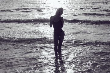 Sexy blonde woman in a red bathing suit is standing in the ocean.