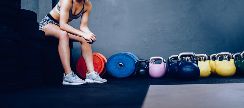Detail of Girl resting sitting on weights in Gym after training