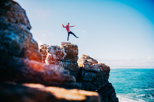 Young man balancing on cliff at the ocean