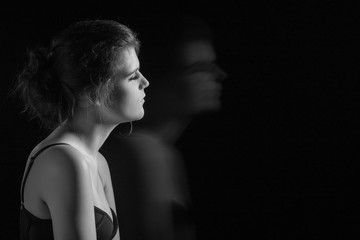 Naklejka premium beautiful young woman and her blurred silhouette on black background with copy space, monochrome
