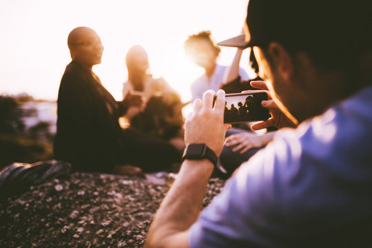 Young Adult Man Taking Photo With Smart Phone Of His Friends