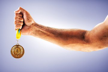 Plakat Man's hand is holding gold medal on a blue background.