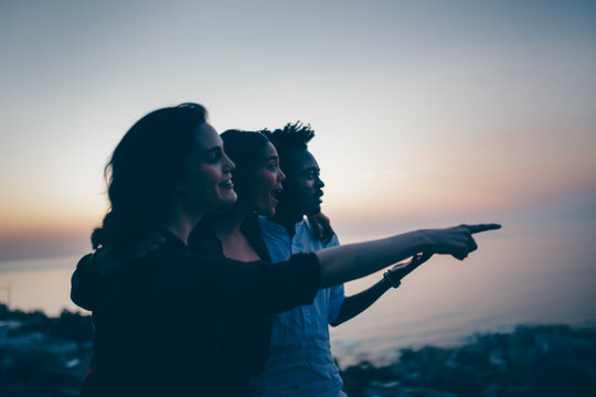 Multi ethnical group of friends standing on cliff together