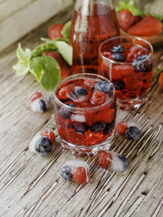 Summer berry lemonade with frozen berries on a wooden rustic table, selective focus