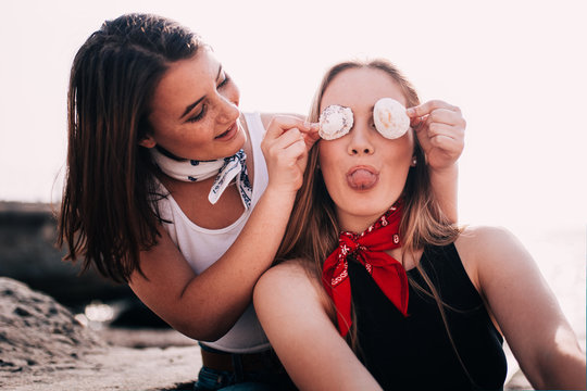 Teenager Girls pulling faces and playing with Sea shell