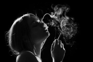 young woman smoking cigarette on black background, monochrome