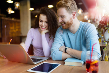 Happy couple spending time at coffee shop working on laptop