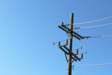 Terminal end of power pole against a deep blue sky
