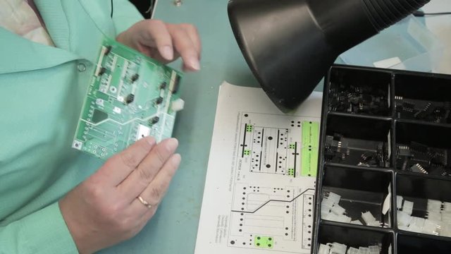 Woman holding pincette and soldering iron instal electronic components on PCB (Printed circuit boards)