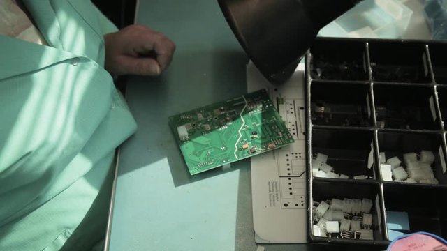 Woman holding pincette and soldering iron instal electronic components on PCB (Printed circuit boards)