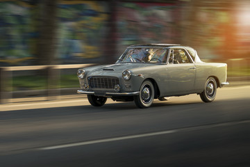 Fototapeta na wymiar Vintage car runs in the city at sunset