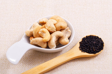 Organic raw Cashew nut in white ceramic bowl and sesame on base napkin