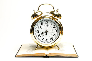 Reloj de metal dorado con Libro abierto sobre fondo blanco aislado. Vista de frente