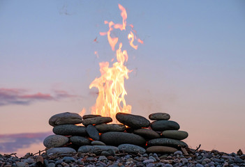 the fire burning in the stone place on the pebbly beach