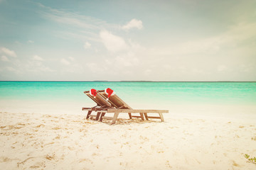 Fototapeta na wymiar Christmas on beach -chair lounges with Santa hats at sea