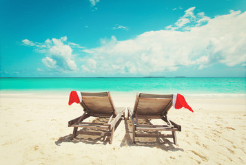 Christmas on beach -chair lounges with Santa hats at sea