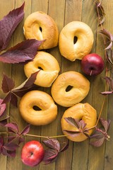 Bagels, apples and autumn leaves on a wooden table