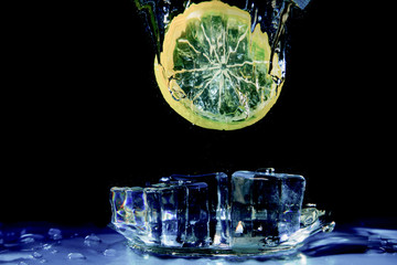 Lime lemon falling in water on black with air bubbles