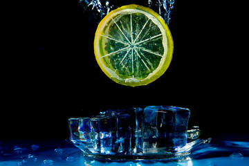 Lime lemon falling in water on black with air bubbles