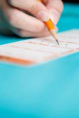 Image of man marking with pencil in lottery ticket