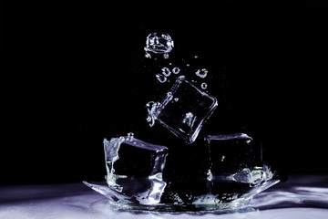 Water splash by ice on black background