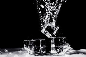Water splash by ice on black background
