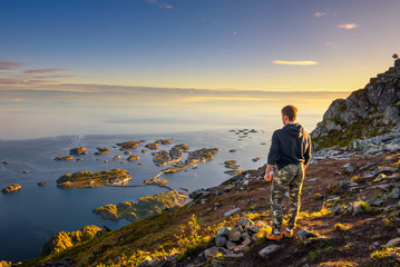Hiker standing at the top of mount Festvagtinden on Lofoten islands in Norway
