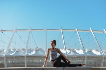 Woman doing yoga exercises outdoors at stadium.Beautiful brunette fit young woman wearing sportswear practicing yoga urban style.Asana, working out,fitness,sport,training and lifestyle concept