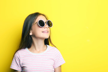 Portrait of beautiful girl with sunglasses on yellow background