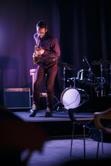 Fototapeta na wymiar Saxophone player in glases performing on stage