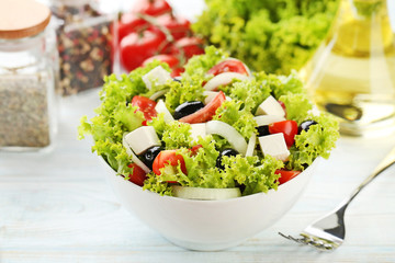 Vegetable salad in bowl with fork on wooden table