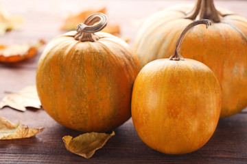 Orange pumpkins with dry leafs on wooden table