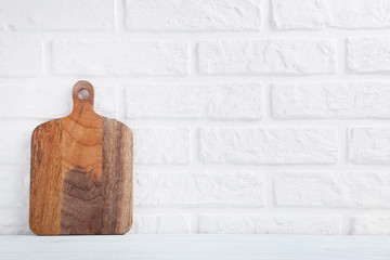 Brown cutting board on a brick wall background