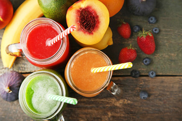 Sweet smoothie in glass jars with fruits on grey wooden table