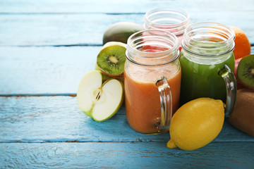 Sweet smoothie in glass jars with fruits on blue wooden table