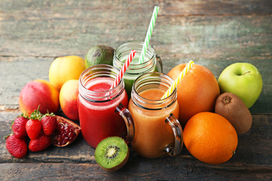 Red smoothie in glass jars with fruits on grey wooden table