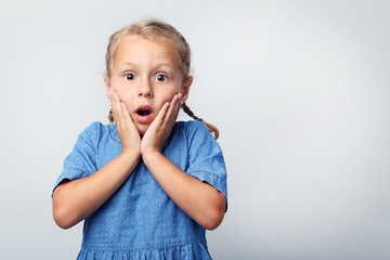 Portrait of little girl in blue dress on grey background