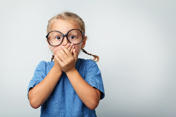 Portrait of little girl with glasses on grey background