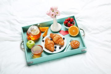Tasty breakfast in bed on wooden tray