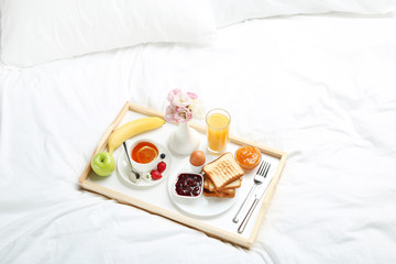 Fototapeta na wymiar Tasty breakfast in bed on wooden tray