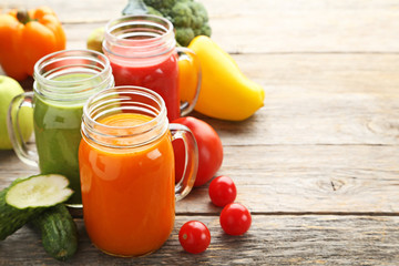 Vegetables smoothie in jars on wooden table