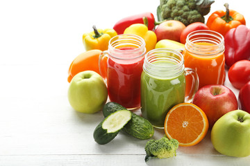 Vegetables smoothie in jars on white wooden table
