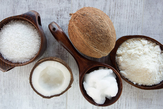 Homemade coconut products on wooden table background. Coconut oil, coconut flour and shredded coconut