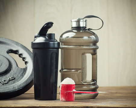 Fitness and sports concept with a  scoop of protein powder necessary nutrition for muscle recovery after an intensive workout, next to a protein shaker