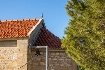 Fototapeta na wymiar Tiled roof of the church and larch branches against the blue sky.
